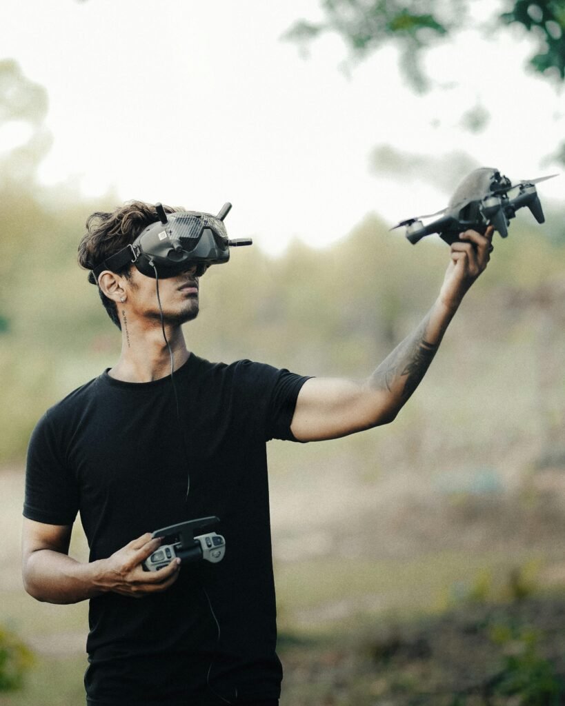 pexels photo 17910790 17910790 Man uses VR headset and remote to control drone in a natural setting, exploring modern technology.
